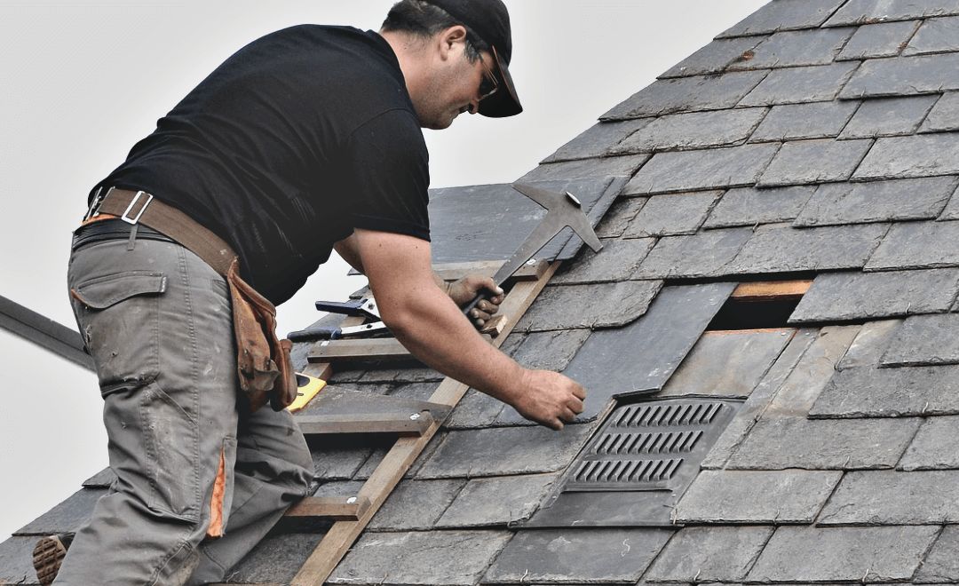Roofer replacing a damaged section near the ridge